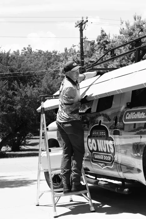 Go Nuts Garage Door technician with a yard sign after completing a job in Cleburne, TX