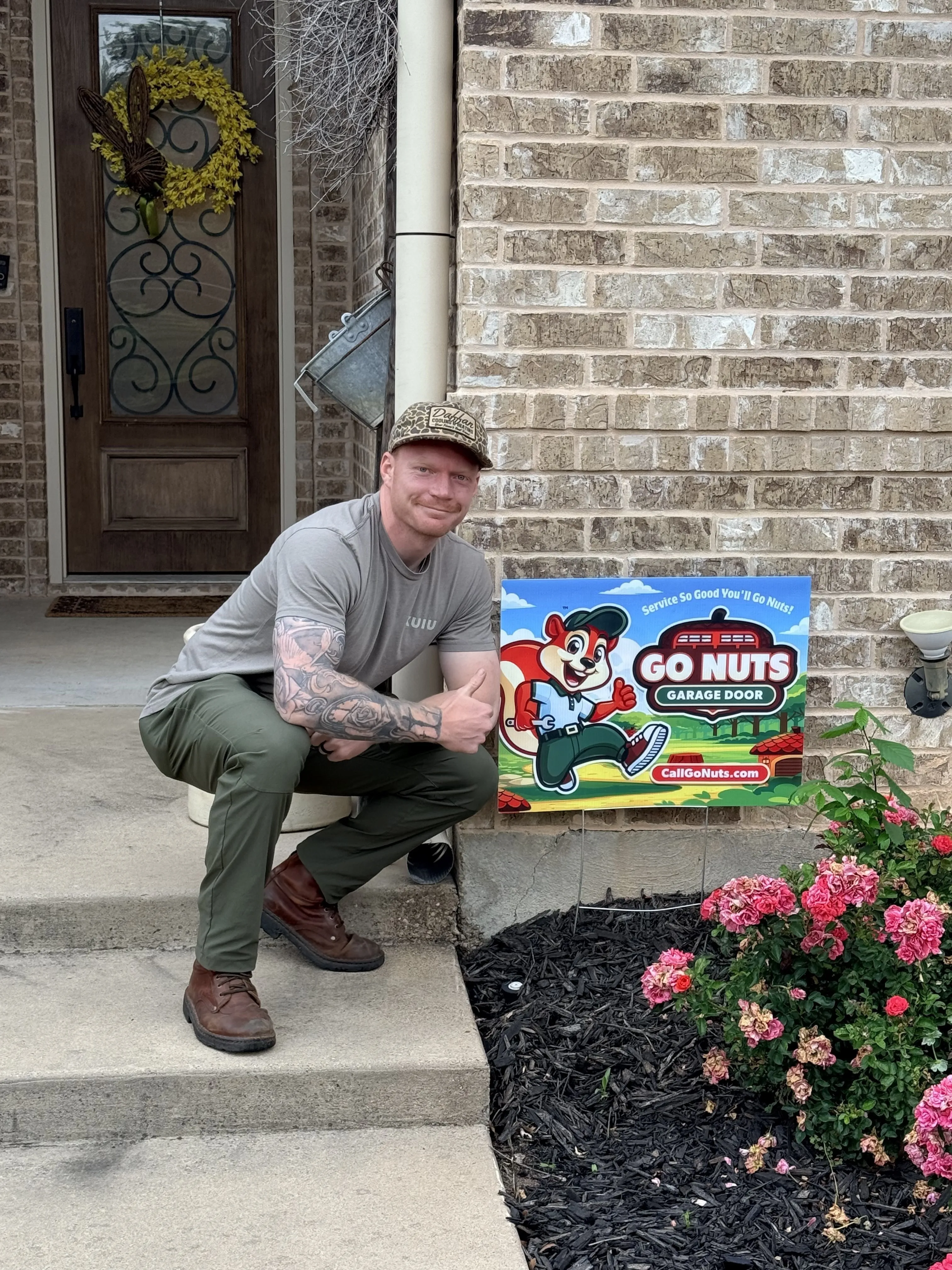 Go Nuts Garage Door technician with a yard sign after completing a job in Aledo, TX